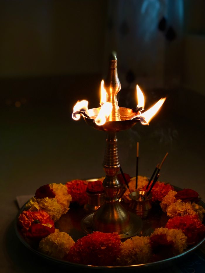 A lit brass oil lamp surrounded by marigold flowers, ideal for Diwali celebrations.